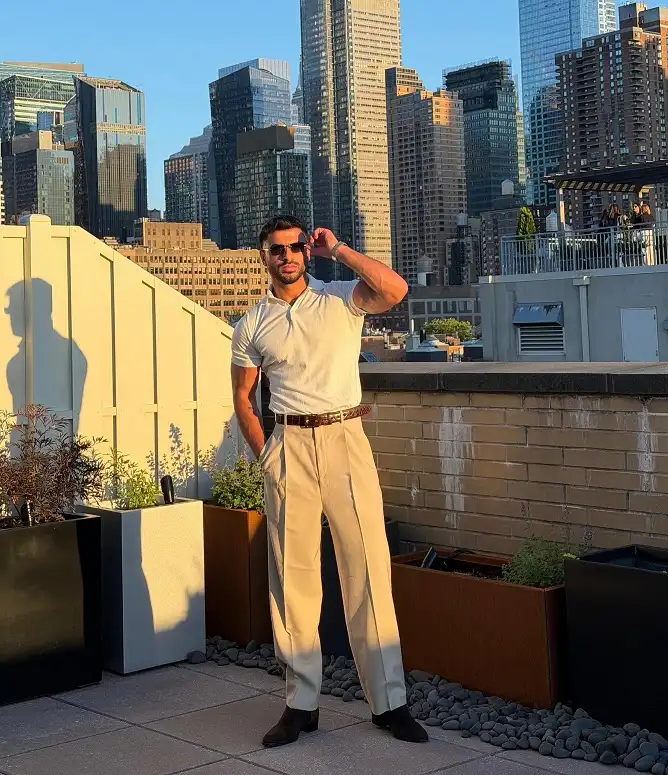 20 Classy Outfit Ideas for Tall Men That Actually Work 17 **Entry 8**## 8. Tonal Cream From Collar to Boot, the Rooftop Ready MoveA short sleeve polo and pleated trousers in nearly the same shade of cream create one long, unbroken column, which does more for height than almost any other color trick on this list. The only real contrast comes from a dark brown crocodile embossed belt and black suede chelsea boots, both small enough to stay accents instead of stealing focus.Sunglasses and a watch round it out without adding bulk. This works because the outfit trusts texture, the ribbing in the polo, the pleat lines in the trousers, to do the visual work that color usually handles. Skip this if you're not comfortable being the brightest thing in the room, because tonal cream tends to draw the eye fast.<div style="overflow-x:auto; margin:24px 0;">
<table style="width:100%; border-collapse:collapse; font-size:15px; color:#4A4A4A;">
<thead>
<tr>
<th style="text-align:left; background:#B3965E; color:#ffffff; padding:10px 12px;">Full Tuck</th>
<th style="text-align:left; background:#895F0E; color:#ffffff; padding:10px 12px;">Half Tuck</th>
</tr>
</thead>
<tbody>
<tr>
<td style="padding:10px 12px; border-bottom:1px solid #e7e7e7; background:#F9F7F2;">Reads sharp and pulled together, ideal for a rooftop dinner or a nicer daytime plan.</td>
<td style="padding:10px 12px; border-bottom:1px solid #e7e7e7;">Feels more relaxed, better for a casual lunch or a walk around the city.</td>
</tr>
<tr>
<td style="padding:10px 12px; border-bottom:1px solid #e7e7e7; background:#F9F7F2;">Needs a belt to look intentional, like the one here.</td>
<td style="padding:10px 12px; border-bottom:1px solid #e7e7e7;">Belt is optional, the shirt hem does the work instead.</td>
</tr>
</tbody>
</table>
</div>Send the next image whenever you're ready.