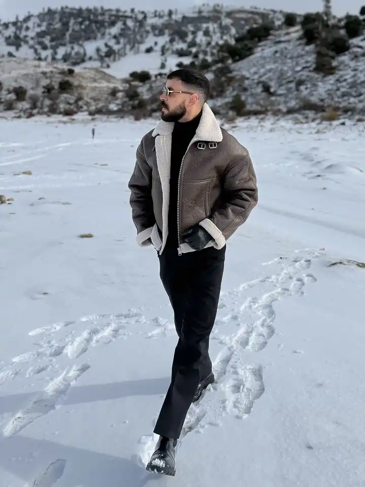 25 Stylish Winter Travel Outfits for Men & Ski Trips 14 Brown Shearling Aviator Jacket With All Black Underneath