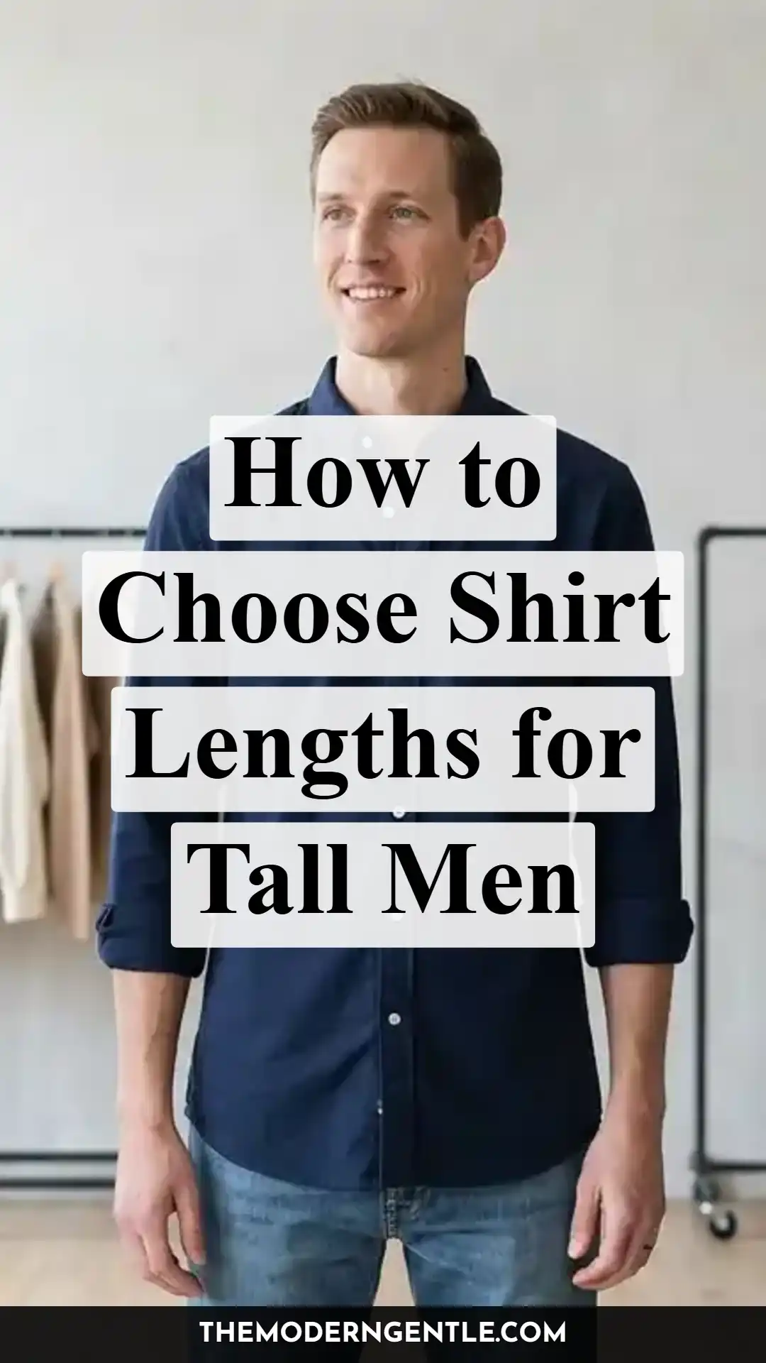 A tall man in a navy button down shirt stands untucked with sleeves rolled to the forearm, paired with jeans against a light grey wall and a clothing rack of beige and cream garments. Bold serif text reads How to Choose Shirt Lengths for Tall Men. The photo highlights proper shirt length and fit for tall men, tying into torso to inseam proportions and tall sizing guidance.
