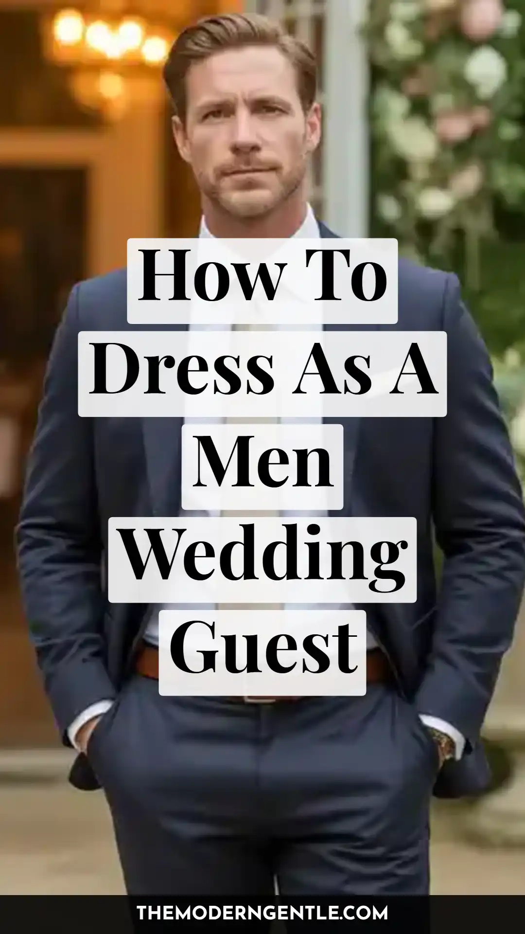 Close-up portrait of a man in a navy suit, white dress shirt, and light neutral tie, hands tucked in his trouser pockets, standing in front of a warm, string-lit venue entrance with greenery and white flowers behind him. Text overlay reads "How To Dress As A Men Wedding Guest," highlighting a formal wedding outfit and men's wedding guest attire suited for evening ceremonies.