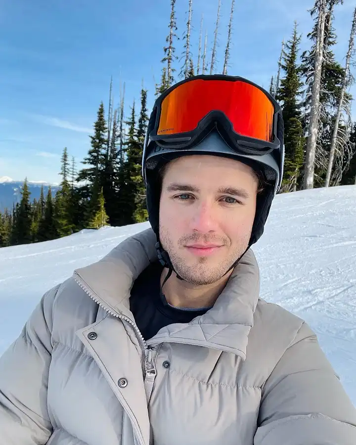 25 Stylish Winter Travel Outfits for Men & Ski Trips 11 Taupe Puffer, Black Helmet and Mirrored Goggles on the Slope