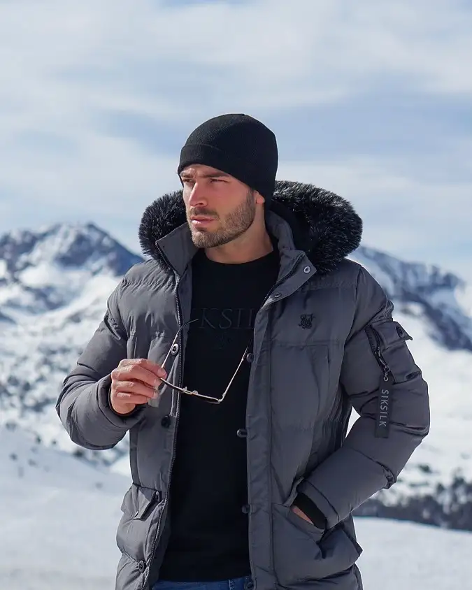 25 Stylish Winter Travel Outfits for Men & Ski Trips 10 Grey Fur Trim Parka Over a Black Tee for Cold Mountain Mornings
