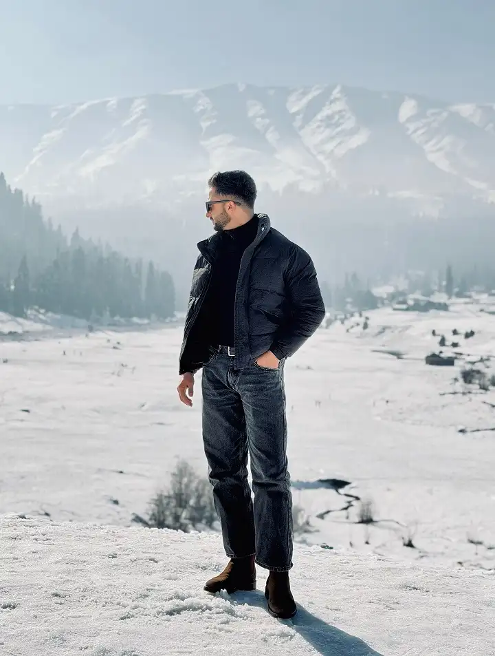 25 Stylish Winter Travel Outfits for Men & Ski Trips 5 Black Puffer Over a Turtleneck With Brown Suede Chelsea Boots