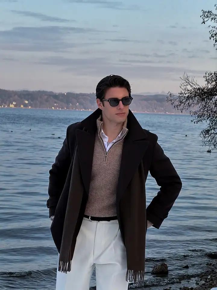 25 Stylish Winter Travel Outfits for Men & Ski Trips 2 Brown Overcoat and Cream Trousers for Dinner by the Lake
