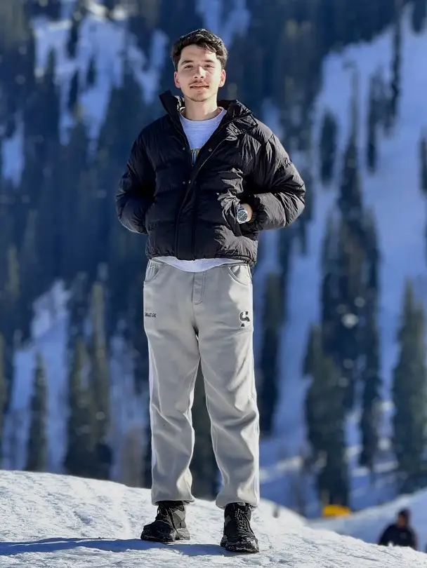 25 Stylish Winter Travel Outfits for Men & Ski Trips 16 Cropped Black Puffer Over Grey Sweatpants for an Easy Snow Day