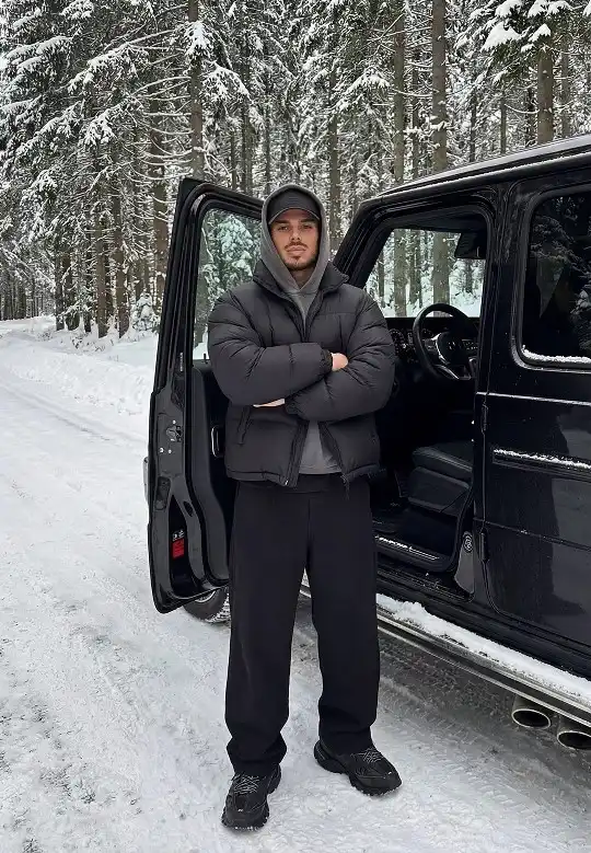 25 Stylish Winter Travel Outfits for Men & Ski Trips 3 All Black Puffer and Hoodie for the Long Drive Up