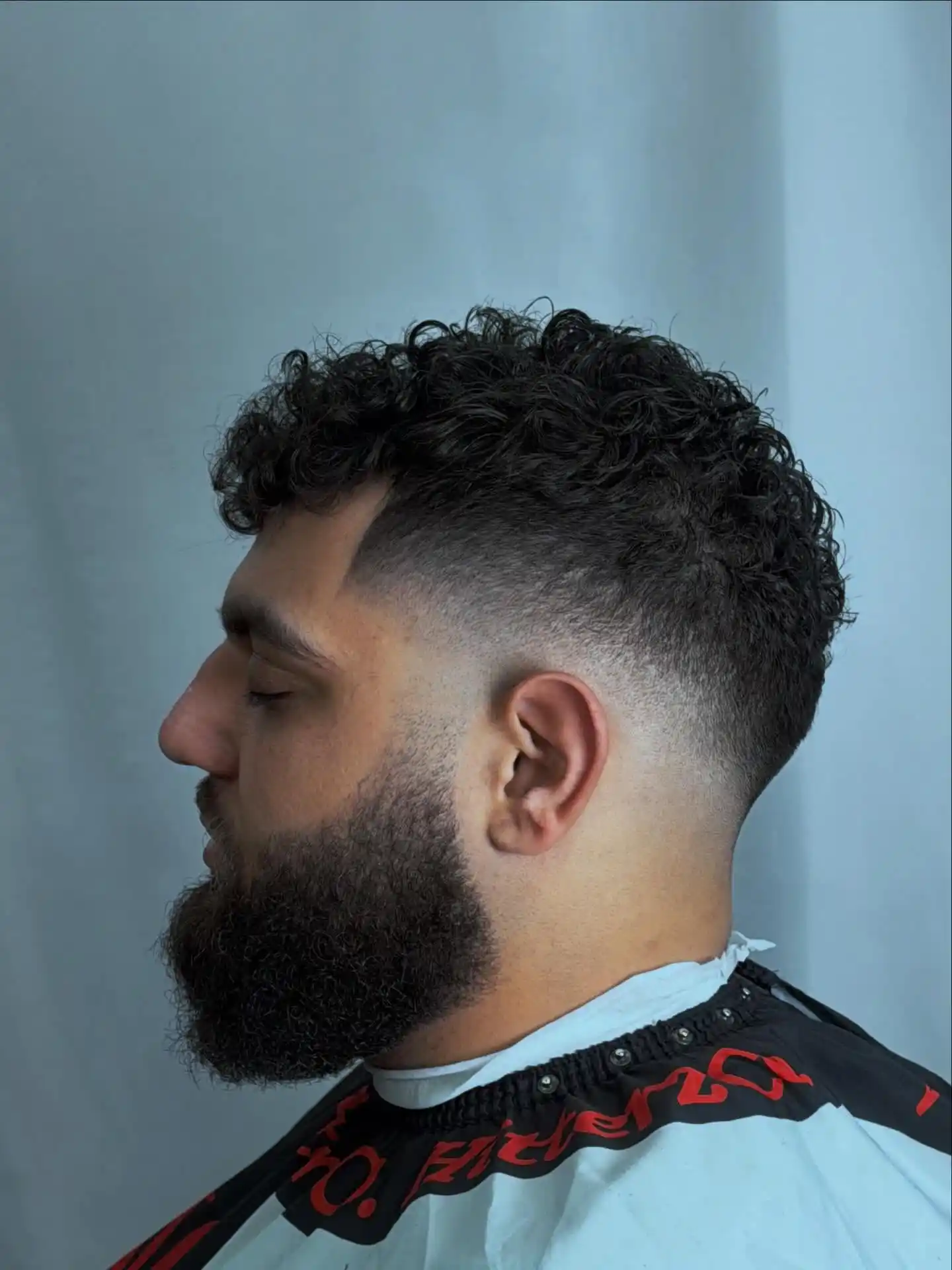8. A Razor Part Cuts Through the Curls Above a Steep, Fast Fade