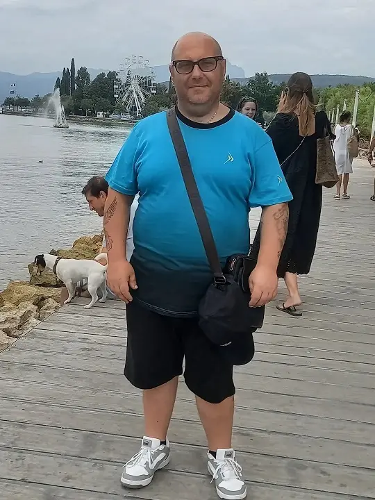 24 Travel Outfit Ideas for Plus Size Men Worth Saving Right Now 8 Bright Tee, Black Shorts, and a Crossbody That Frees Both Hands