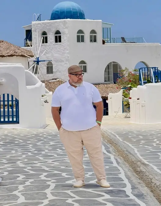 24 Travel Outfit Ideas for Plus Size Men Worth Saving Right Now 3 White Polo and Cream Chinos Against Whitewashed Walls